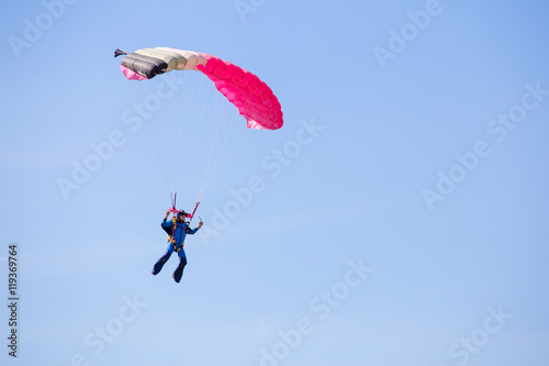 skydiver with pink gray parachute on clear blue sky