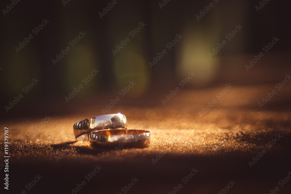 Blurred picture of sparkling wedding rings lying on the brown cl Blurred picture of sparkling wedding rings lying on the brown cl