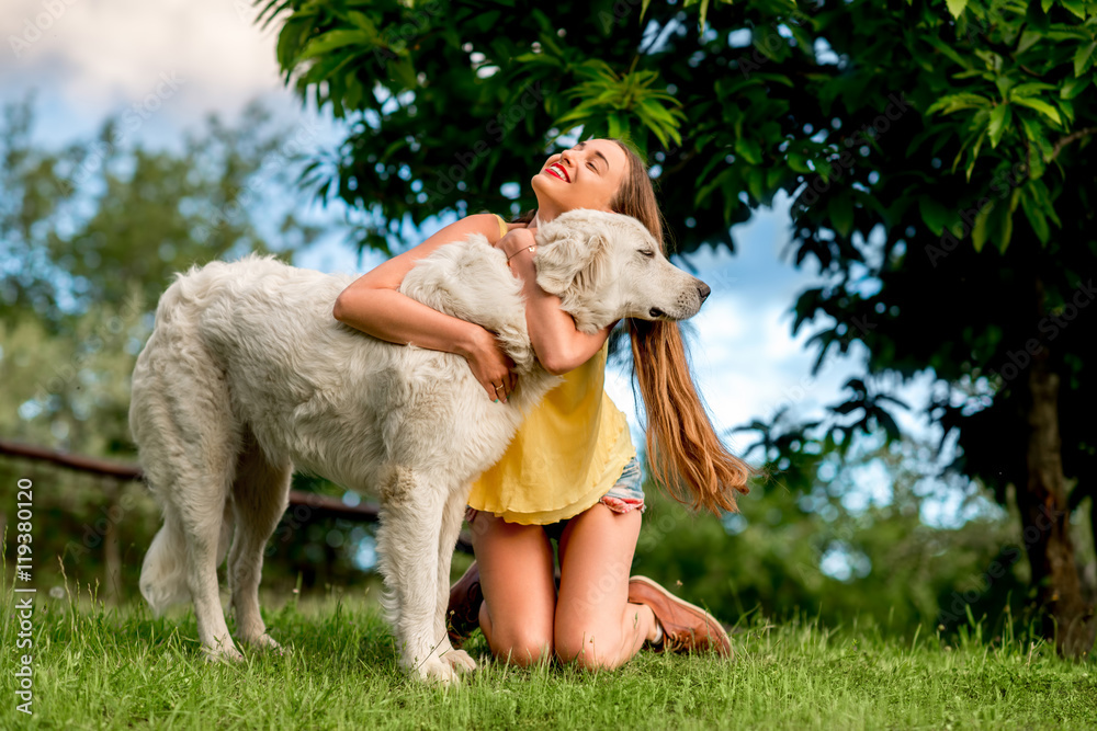 Φωτογραφία Young and happy woman playing with Maremma italian sheepdog on the lawn in the c