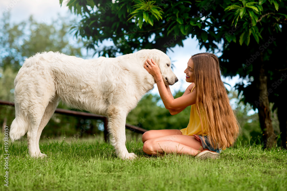 Φωτογραφία Young and happy woman playing with Maremma italian sheepdog on the lawn in the c