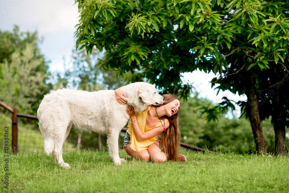 Φωτογραφία Young and happy woman playing with Maremma italian sheepdog on the lawn in the c