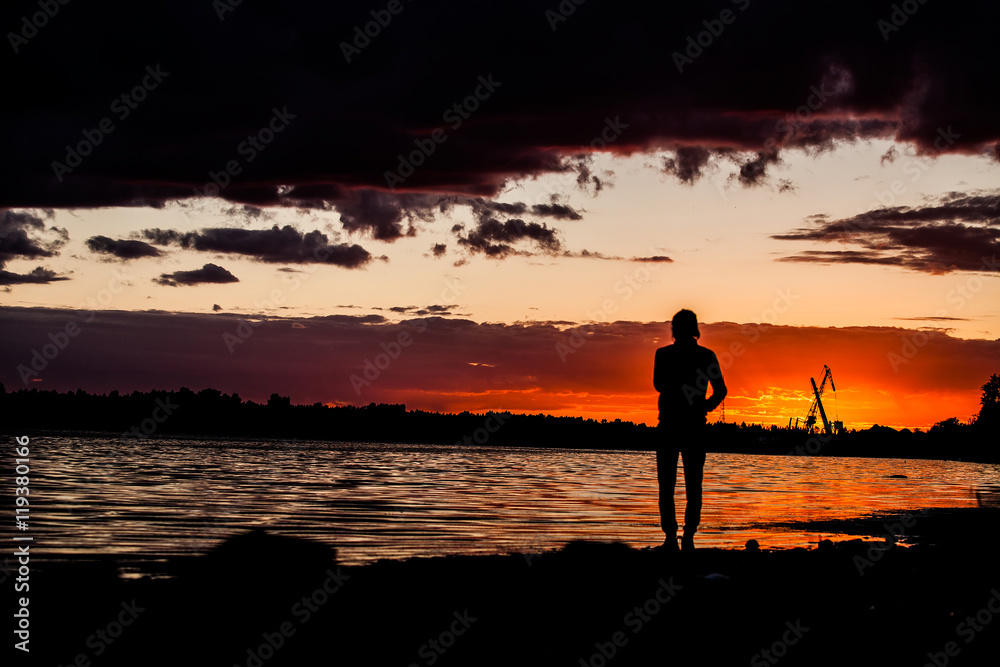 Silhouette of man with their hands in the sunset on the ocean
