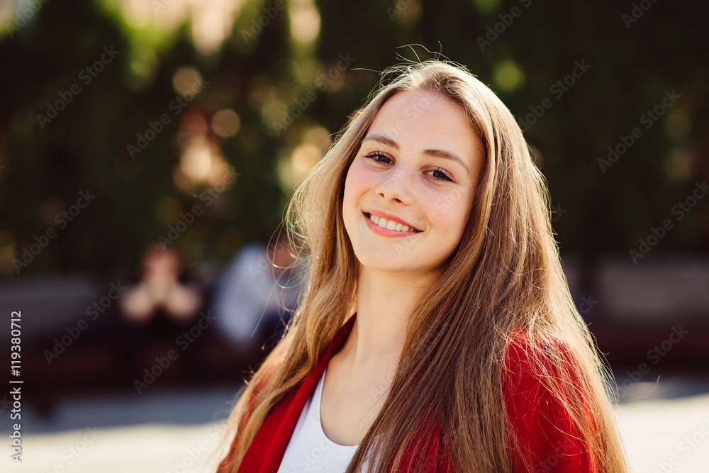 Young girl in red jacket stands outside in sunny weather Young girl in red jacket stands outside in sunny weather