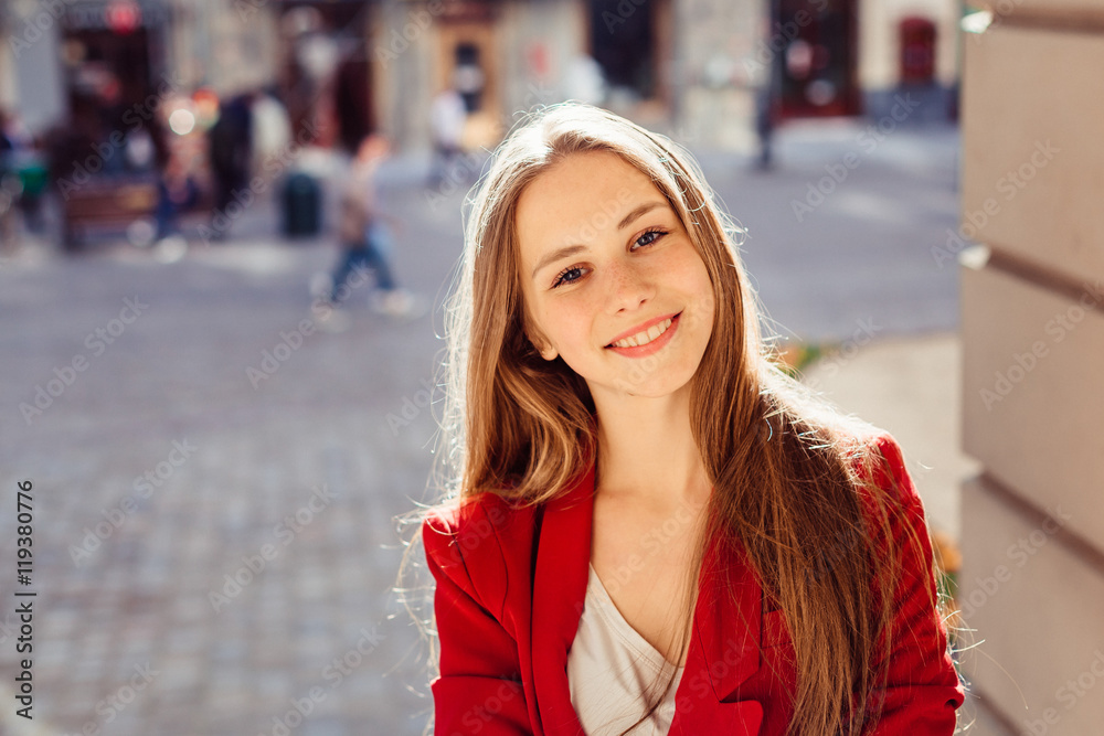 Young girl with beautiful smile leans to the column while posing