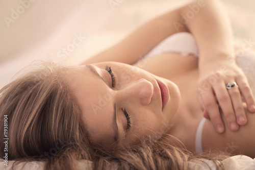 Young woman touches her shoulder while lying on the bed