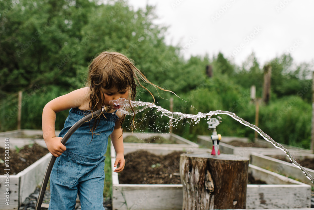 Young girl drinking water from a hose Stock Photo | Adobe Stock
