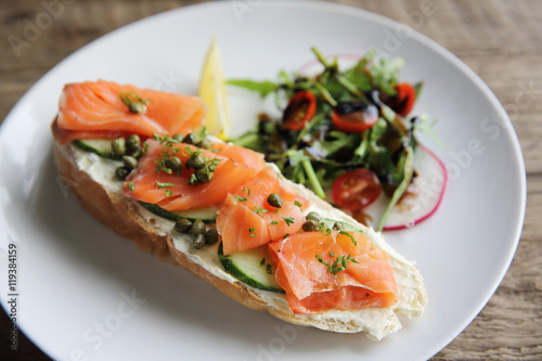 smoked salmon on toasted bread with cream fresh, lemon and salad
