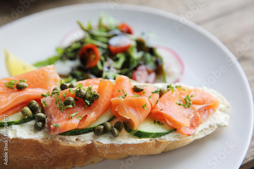 smoked salmon on toasted bread with cream fresh, lemon and salad