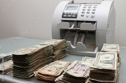 Принти на полотні Stacks of cash next to a money counting machine.