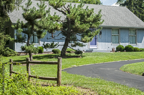 Blue country house with wooden fence and asphalt driveway