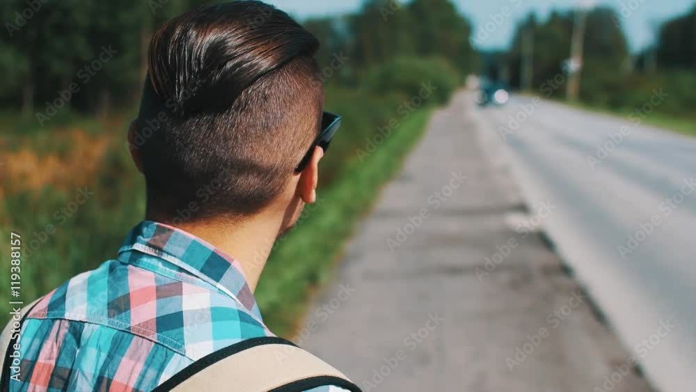 Young boy in sunglasses hitchhiking at road in summer day. Tourist. Thumb up. Traveling. Countryside. Young boy in sunglasses hitchhiking at road in summer day. Tourist. Thumb up. Traveling. Countryside.