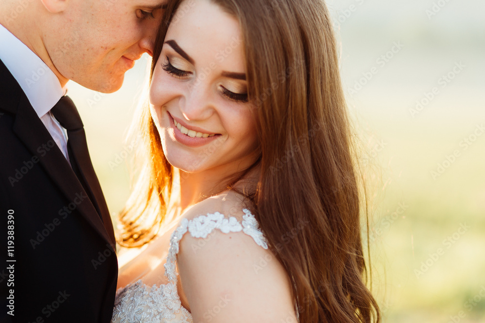 Golden rays of evening sun beautify pretty bride leaning to a gr Golden rays of evening sun beautify pretty bride leaning to a gr