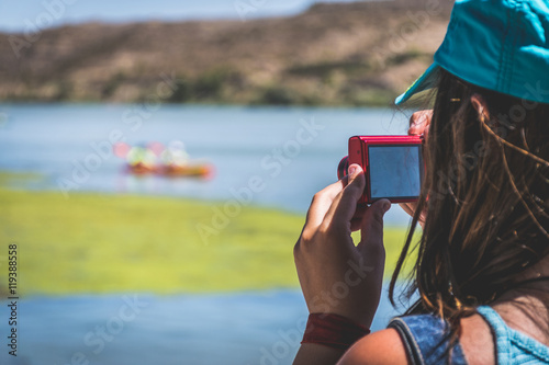 chica tomando fotografía a una piragua del río photo