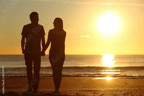 Couple silhouette walking together on the beach