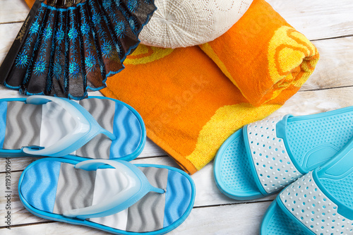 Pair of blue slippers and orange towel on wood. Vacation in summer