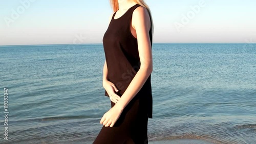 beautiful girl model walks on the shore beach. the wind, the sea breeze develops hair romantic sexual young woman, girl look love looking at the camera, weekend by the sea, beautiful sea calm