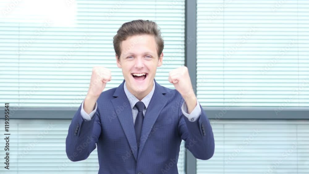 Excited Young Businessman Celebrating Successful Project Completion Excited Young Businessman Celebrating Successful Project Completion