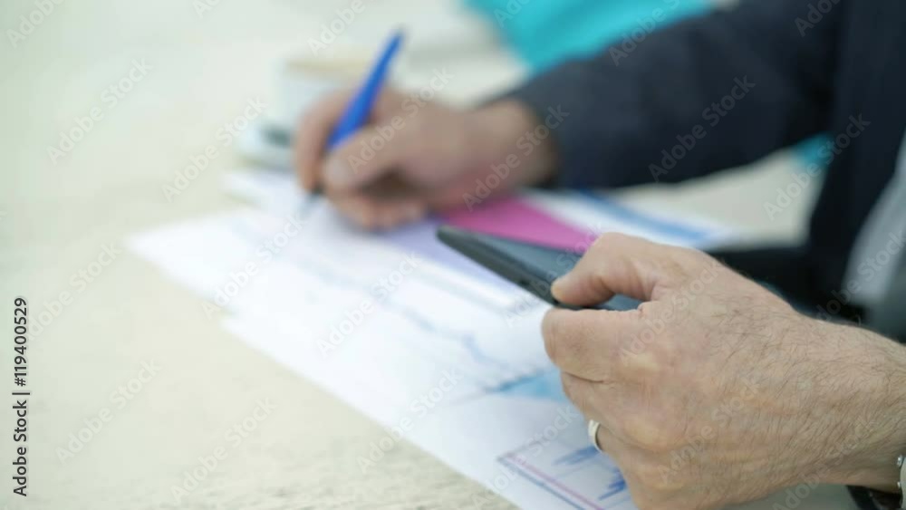 Close up of eldery man hands using phone and writing down the diagrams. 4K