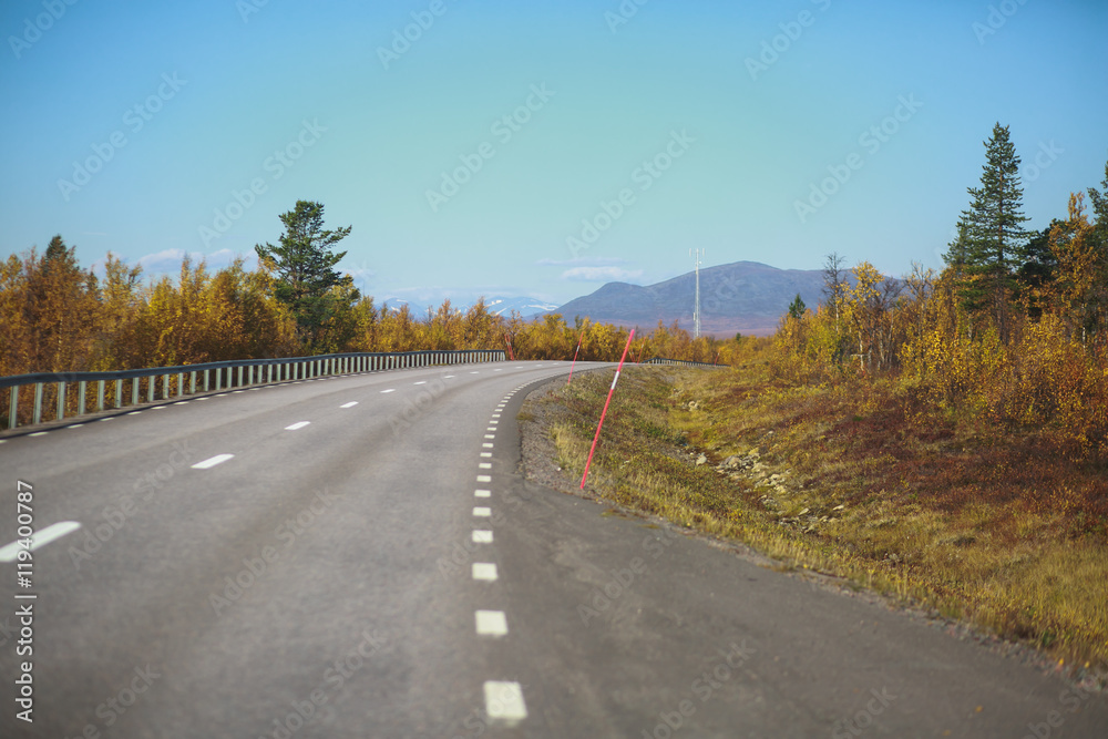 Beautiful vibrant fall autumn landscape of national park near border of Finland, Sweden and Norway, with mountains, camping place, road and forest