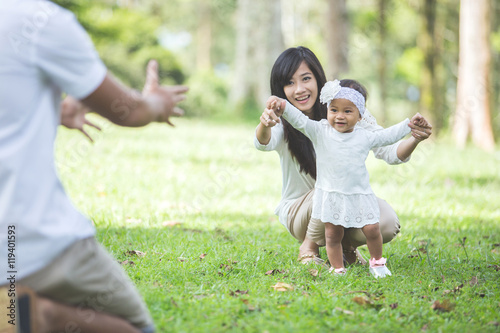 baby learn to walk with their parent in the park photo