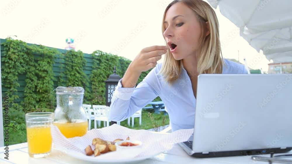 Young, happy woman eating salad in cafe in city