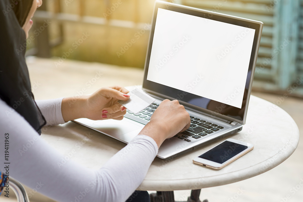 Muslim woman using laptop computer with blank copy space screen while sitting in cafe,flare sun. Muslim woman using laptop computer with blank copy space screen while sitting in cafe,flare sun.