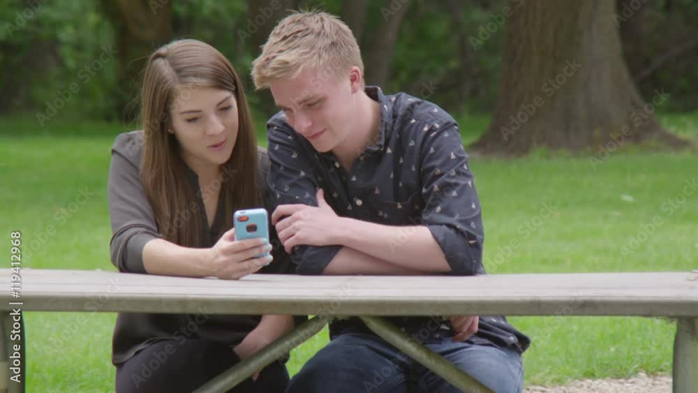 Young couple using cellphone in the park