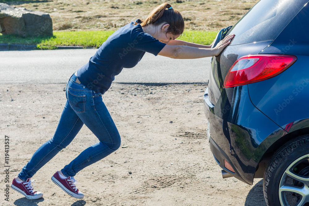 junge frau schiebt ein auto an Stock-Foto | Adobe Stock