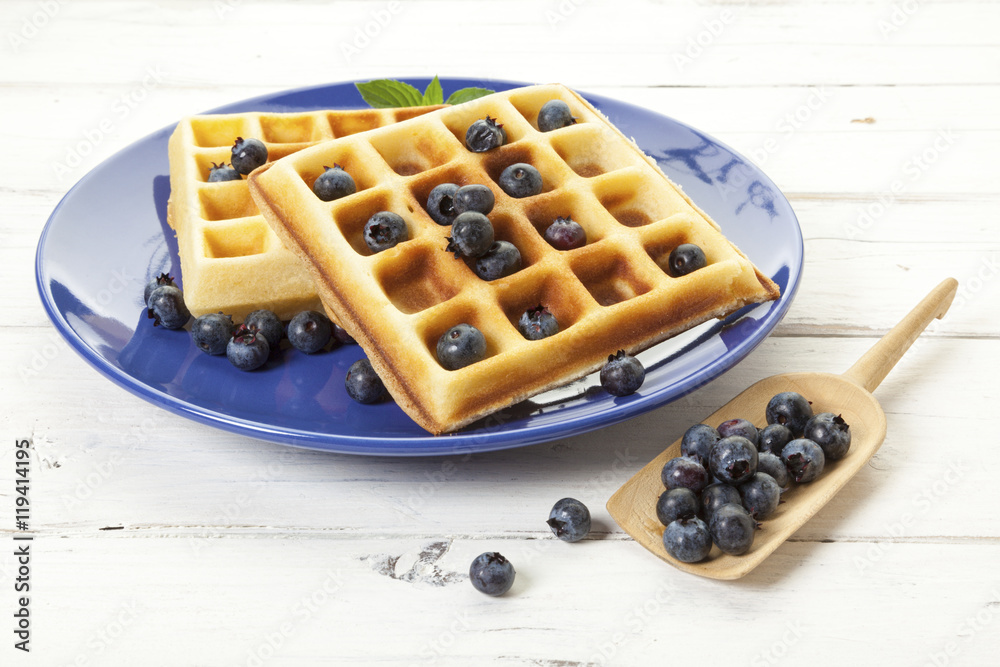 Belgian waffles with blueberries on blue plate
