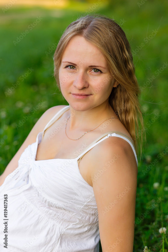 portrait of a pregnant woman sitting on the grass portrait of a pregnant woman sitting on the grass