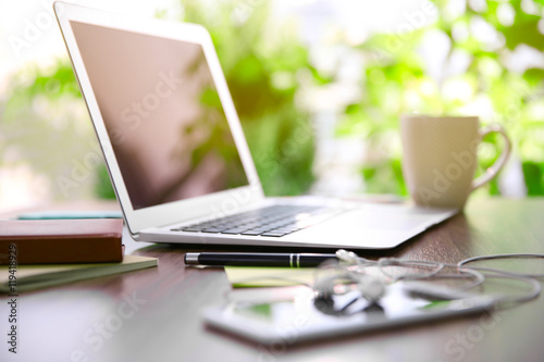Female hands working with a laptop outdoor on blurred green plant background