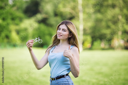 Young girl holding cardboard figure of bicycle outside