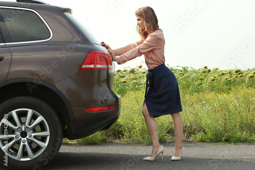 Pretty young woman pushing car