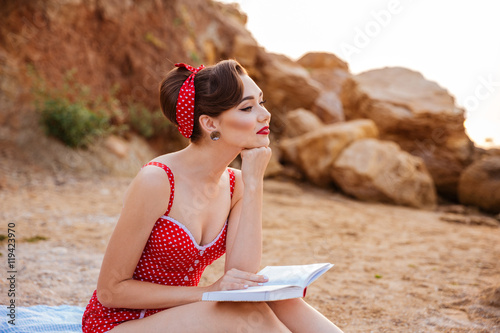 Young beautiful pensive pin up girl sitting with book