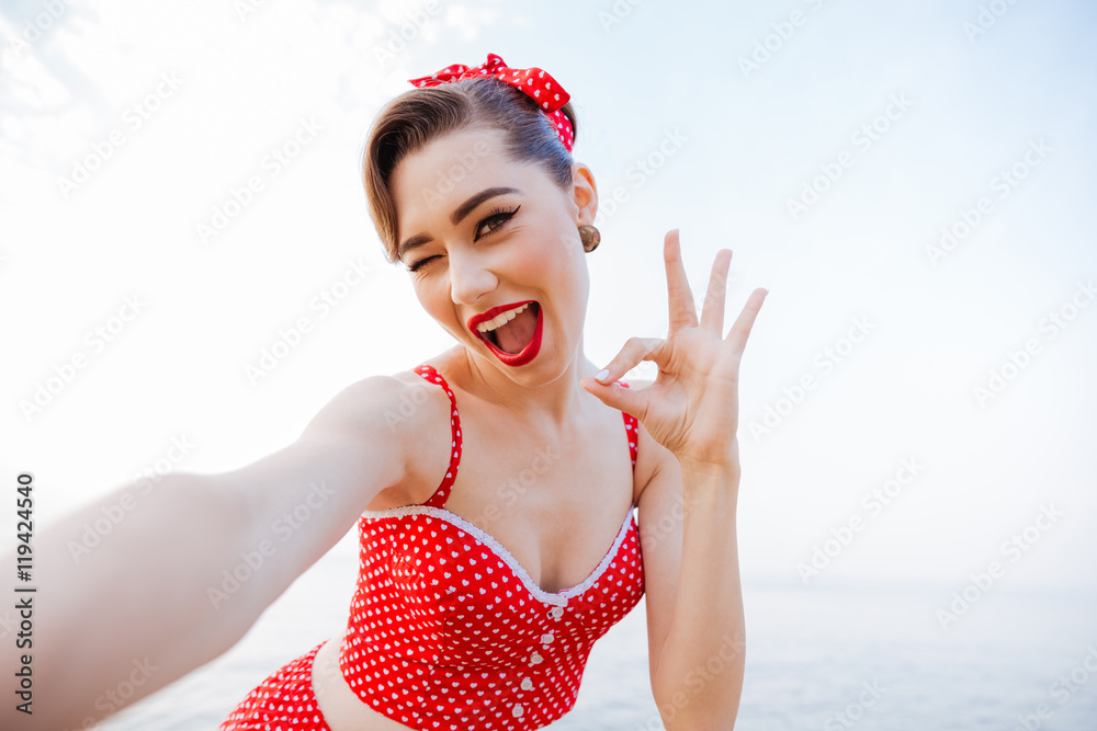 Happy pretty pinup girl in red swimsuit showing okay sign Happy pretty pinup girl in red swimsuit showing okay sign