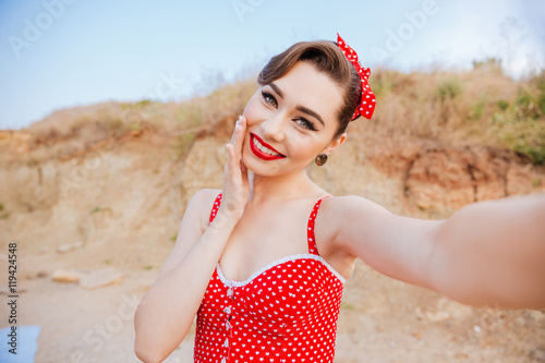 Smiling young cheerful pin up girl making selfie