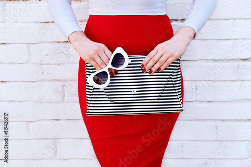 Fashionable woman in red skirt with striped clutch