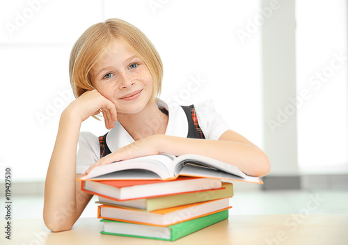 Smiling girl with many books at school
