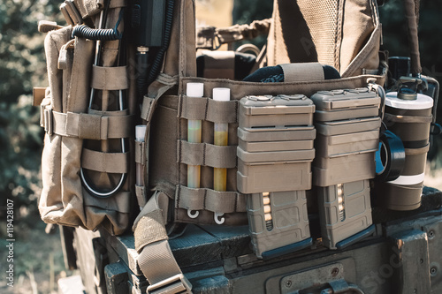 Army vest with a walkie-talkie charged collars stun grenades luminous sticks standing on a wooden box of ammunition.