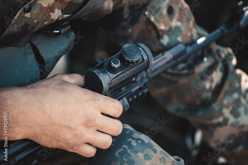A soldier adjusts optical sight on a rifle.