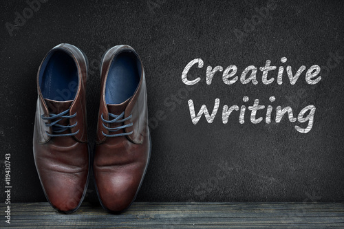 Creative Writing text on black board and business shoes