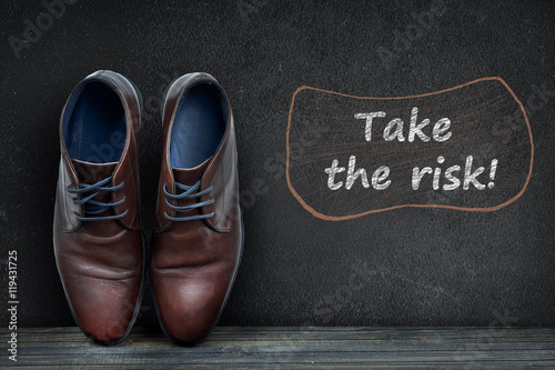 Take the risk text on black board and business shoes