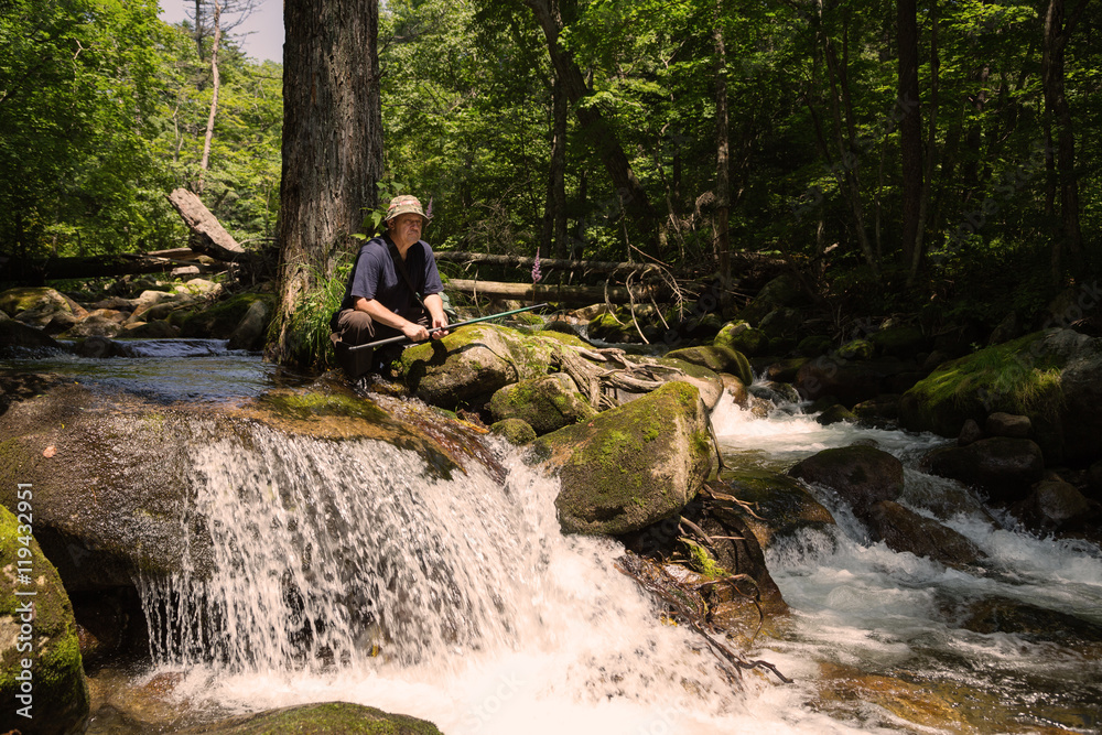 Fisherman has a rest at the mountain river Fisherman has a rest at the mountain river