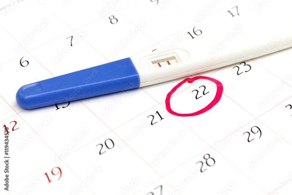 Pregnancy test with positive result lying on calendar Pregnancy test with positive result lying on calendar