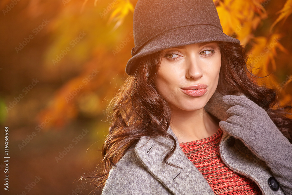 Beautiful elegant woman standing in a park in autumn
