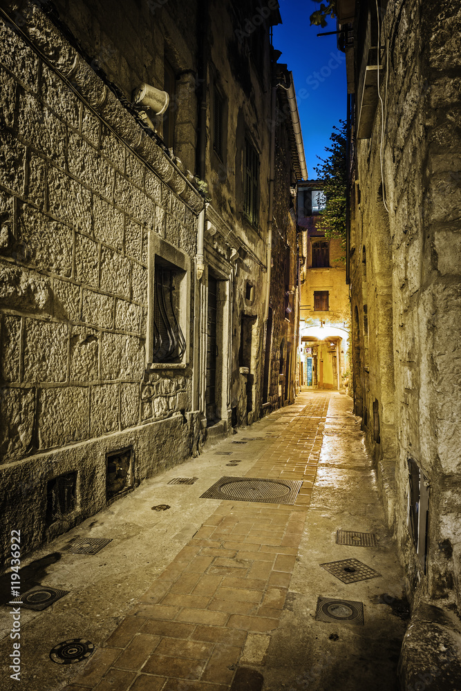 Narrow cobbled street in old town at night, France.