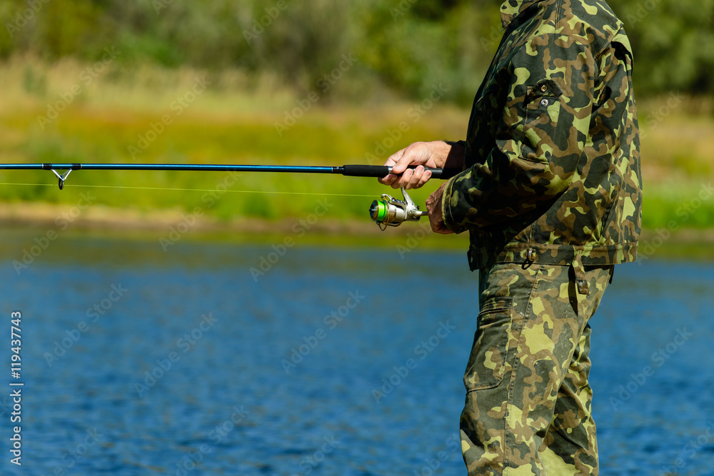 fisherman with a fishing tackle catches a fish on the shore fisherman with a fishing tackle catches a fish on the shore