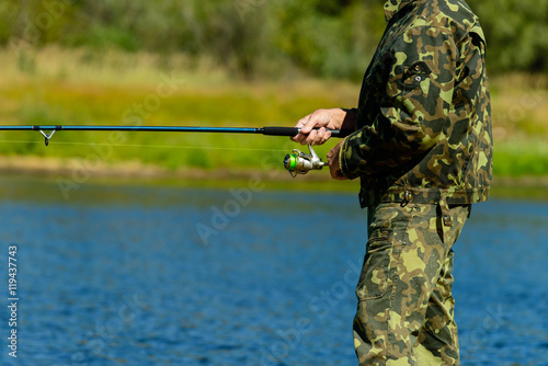fisherman with a fishing tackle catches a fish on the shore
