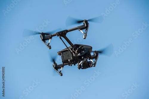 Drone flying in the sky/Drone-quadrocopter with camera hovers on the blue sky