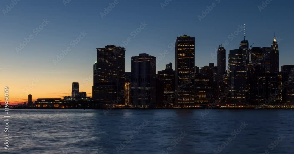 New York City skyscrapers between sunset and dusk with city lights. Time lapse cityscape view of Lower Manhattan Financial District and East River New York City skyscrapers between sunset and dusk with city lights. Time lapse cityscape view of Lower Manhattan Financial District and East River